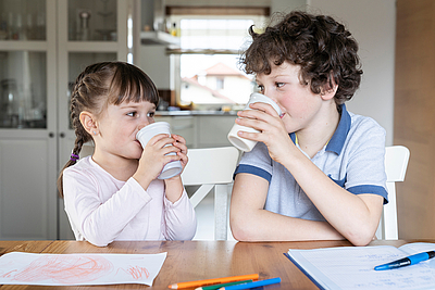 Zwei Kinder trinken Schulmilch aus rPET Bechern