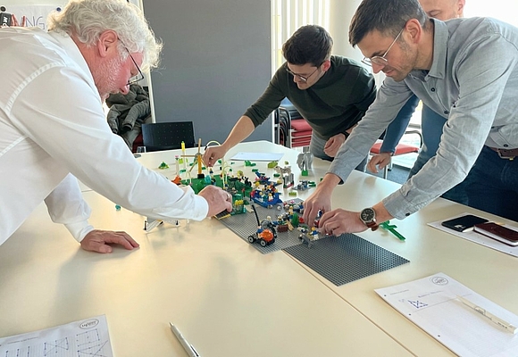 3 Teilnehmer bauen auf einer Plattform mit Lego etwas auf ©Business Upper Austria